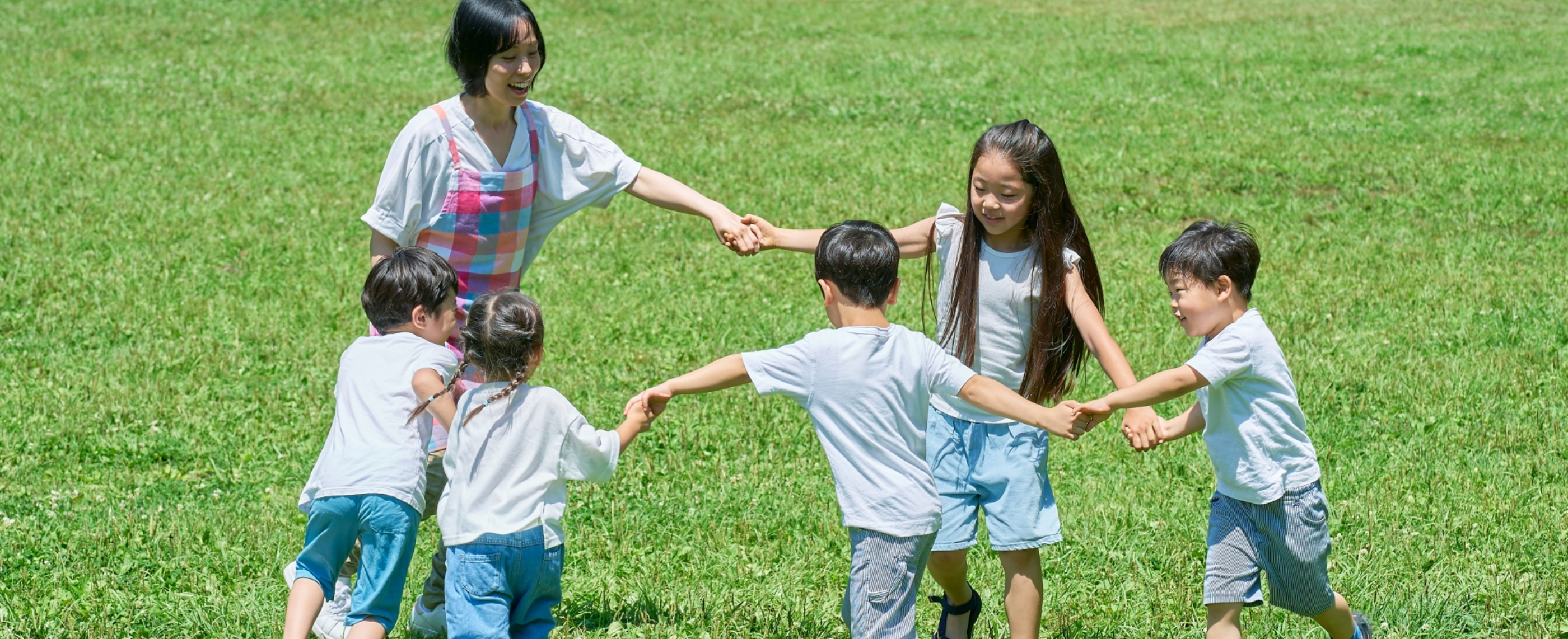 先生と子どもたちが手を繋いで遊んでいる様子